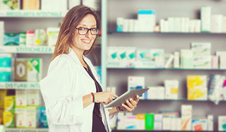 White woman pharmacist standing behind counter in dispensary